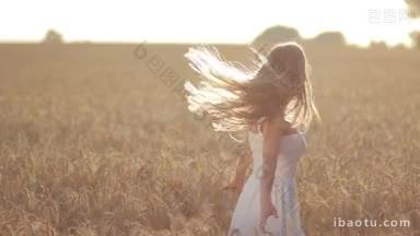 快乐的金发女人穿着白色的裙子在金色的麦田里旋转在美丽的日落在夏天的光辉兴奋